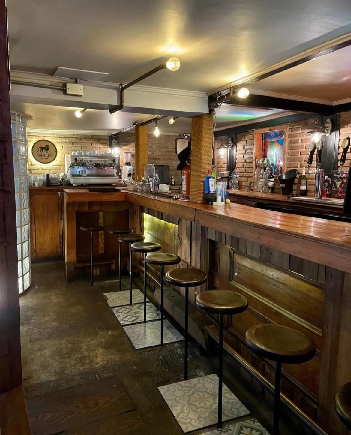 El bar: barra de madera con pisos altos, botellas en repisas y una máquina de café.